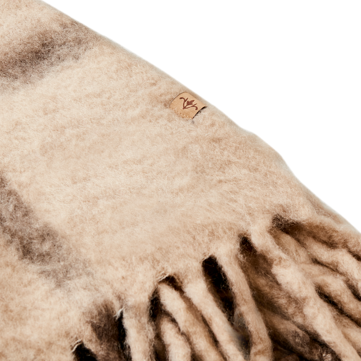Närbild på mjukt ruggad textur och logotyp på beige ullmixfilt