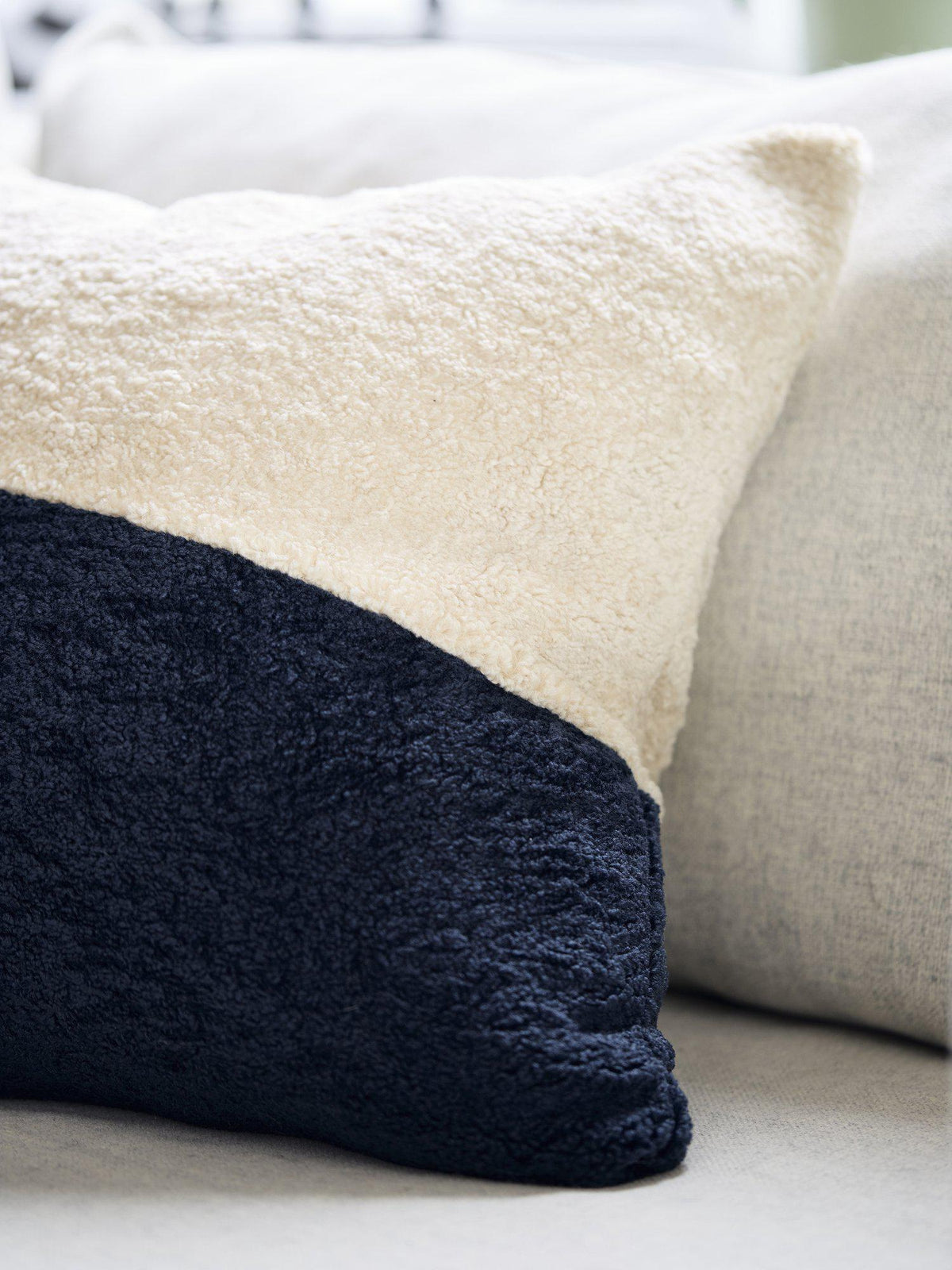 Närbild på blått Austin kuddfodral i fluffigt material på en soffa