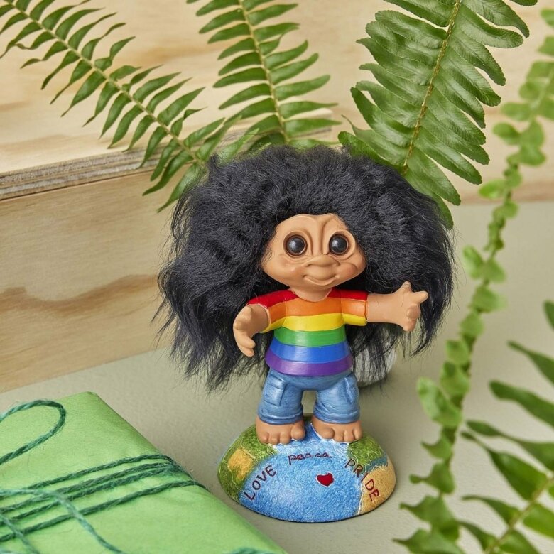 Närbild på Lyckotrollet Pride stående på en dekorativ bas med texten Love Pride