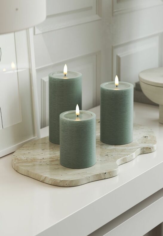 Ett tänt Unique LED-ljus i färgen Sage Green med handgjord finish