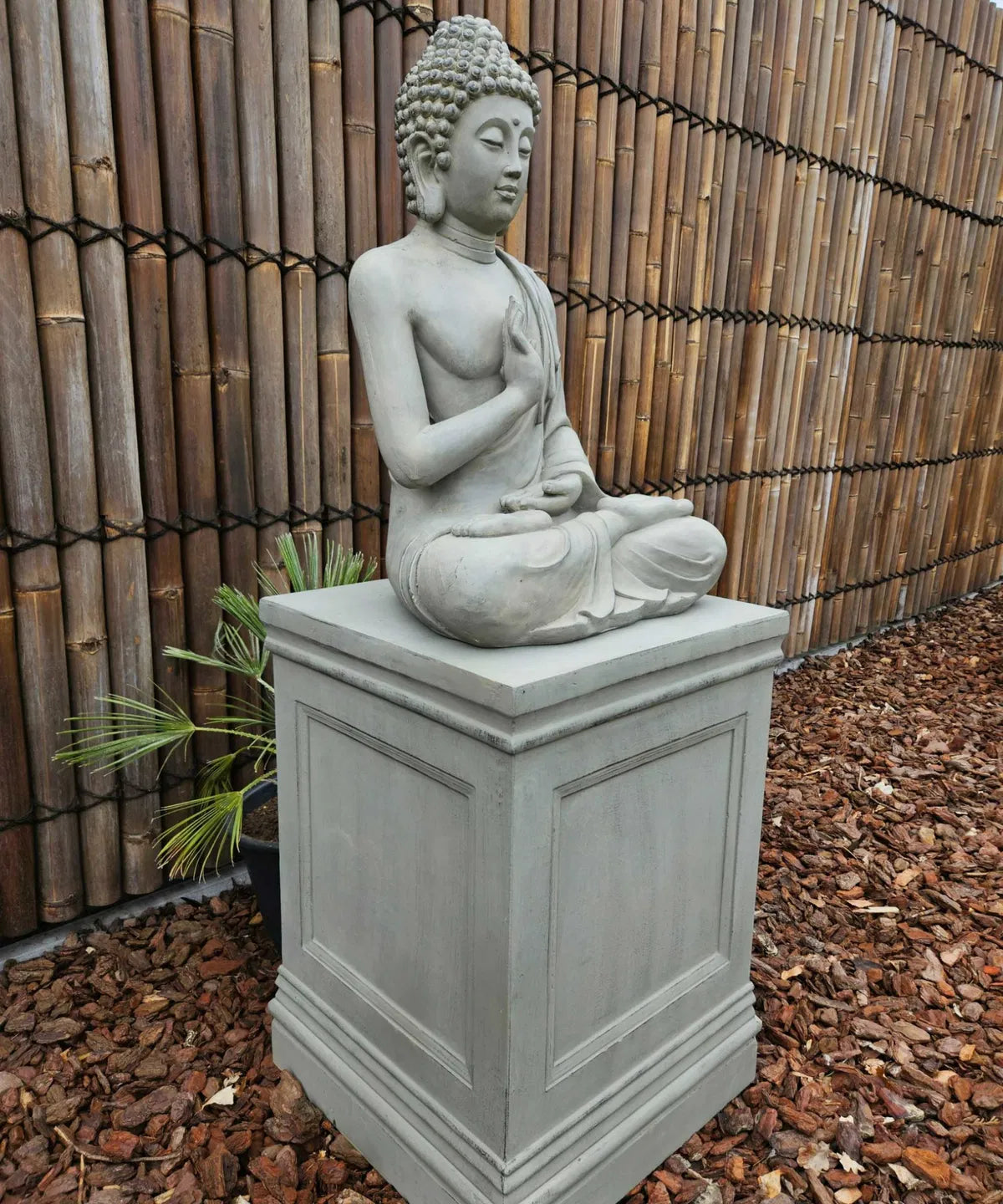 Väderbeständig Buddhastaty i grått som dekoration på en uteplats