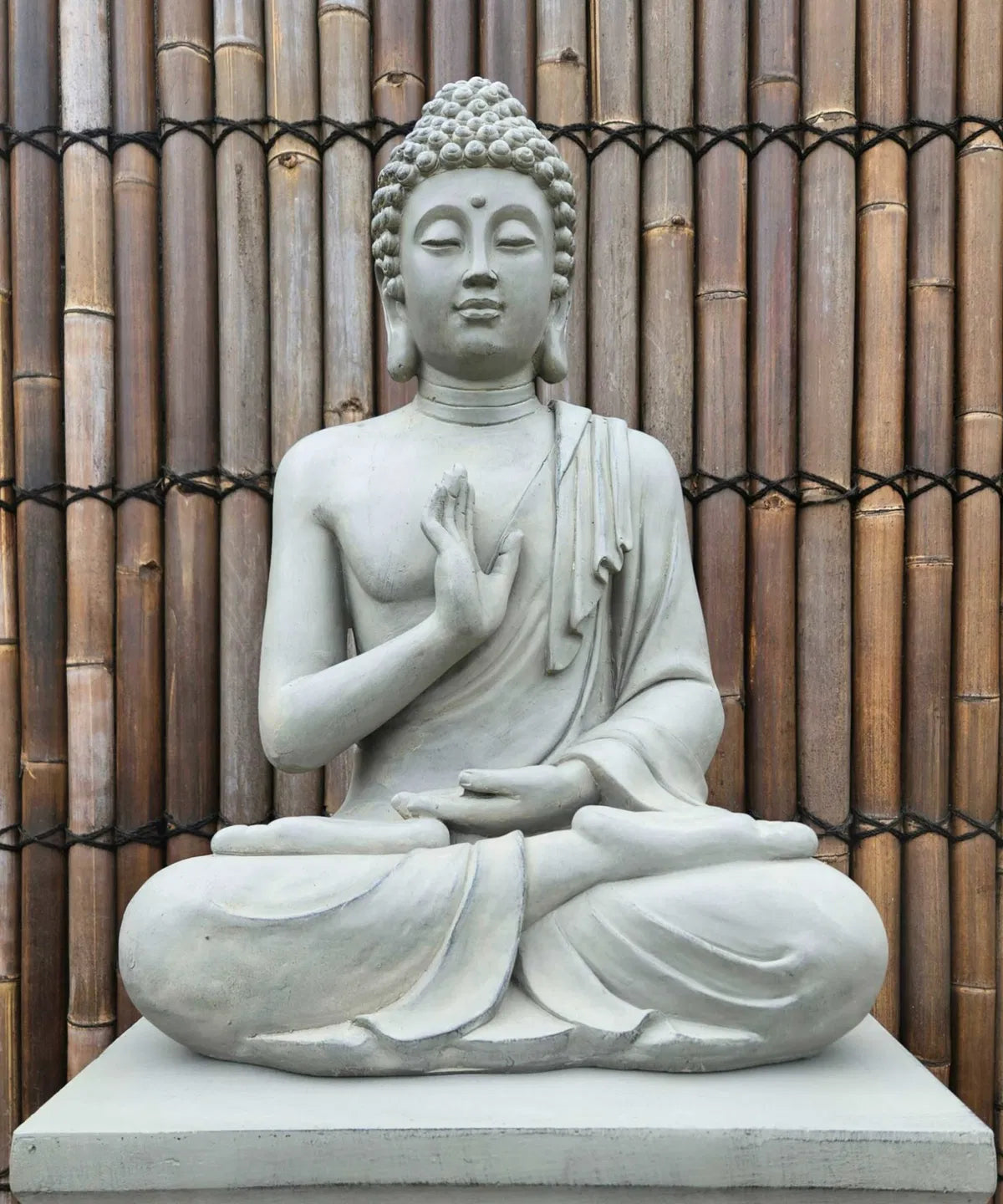 Närbild på en grå Buddhastaty med harmoniskt ansiktsuttryck utomhus