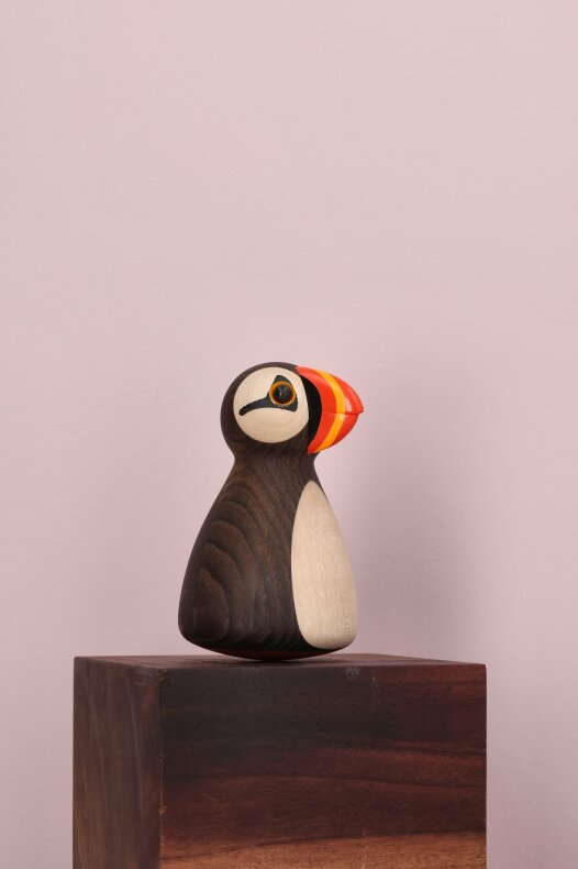 Träfigur Puffy lunnefågel placerad på mörkt träblock i ett lantligt hem
