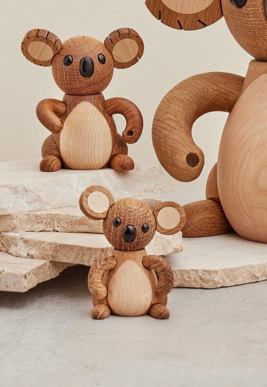 Tre koalafigurer i olika storlekar på rustika stenskivor i ett gårdshus