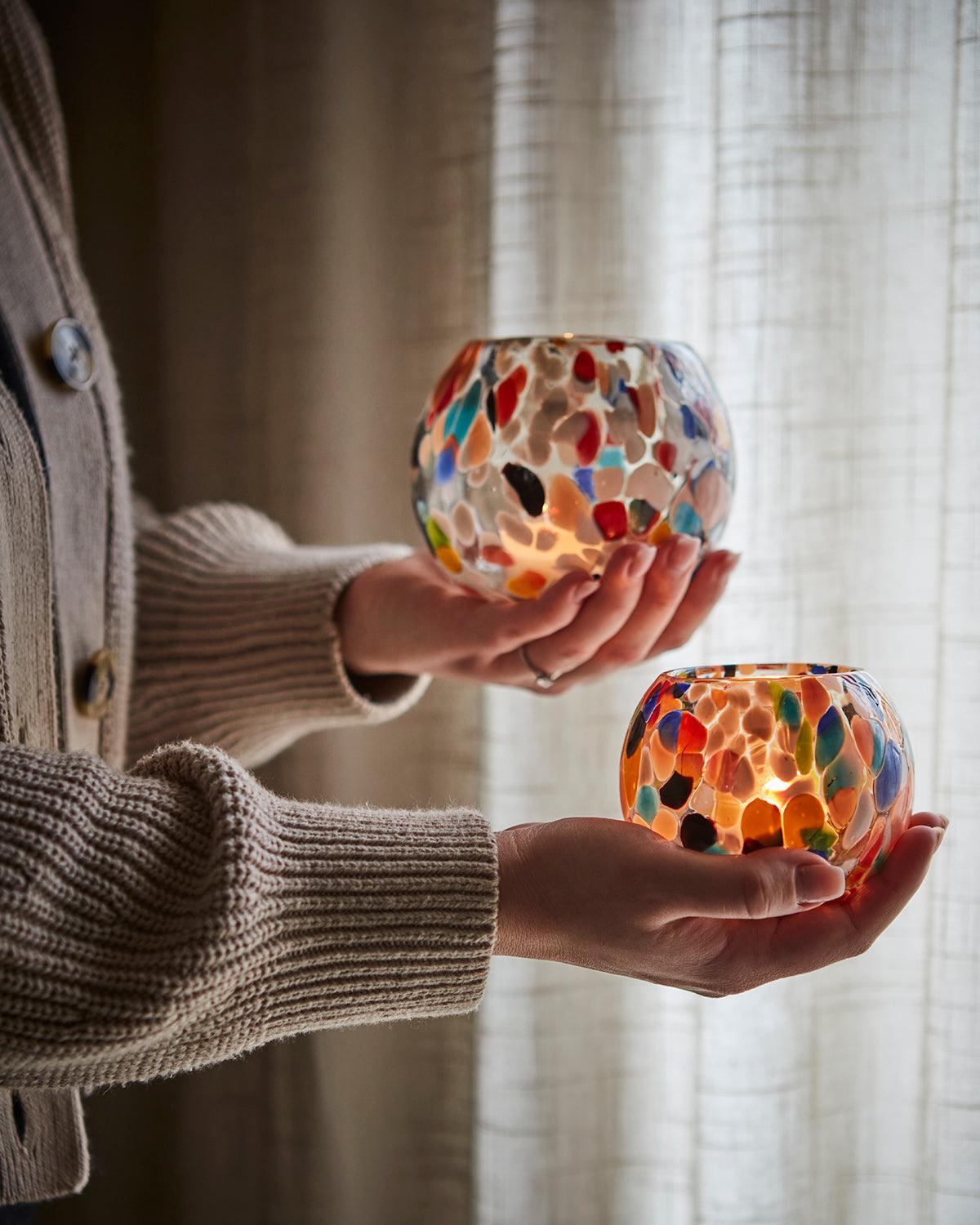 Närbild på rund PARTY ljushållare i glas med färgstarka detaljer