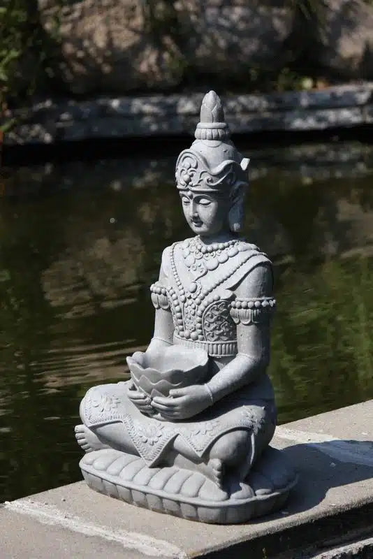 Trädgårdsfigur Guanyin i fiberlera sedd från sidan vid vattenbryn